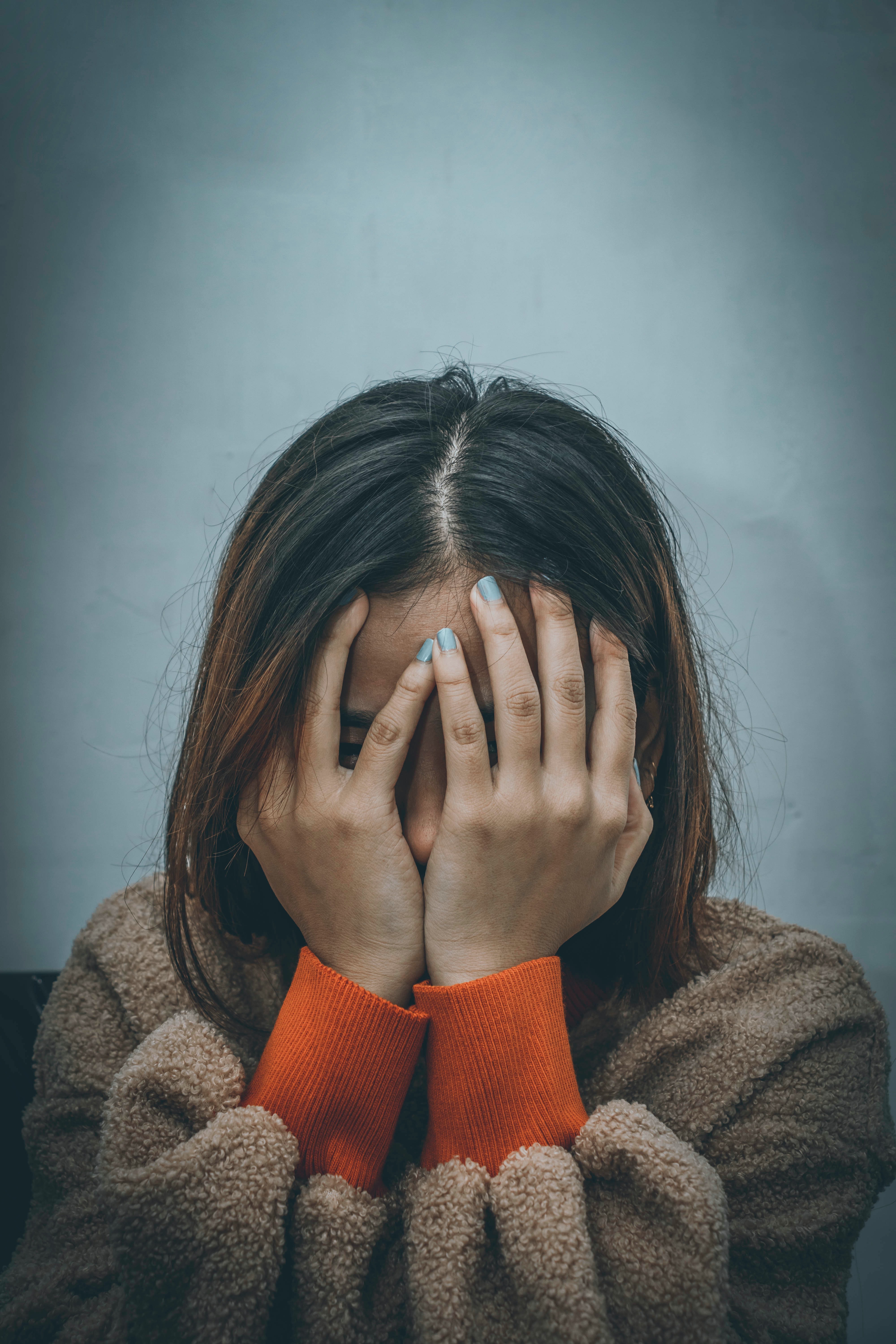 Importance of mental health awareness. A women holding her hands to her face.